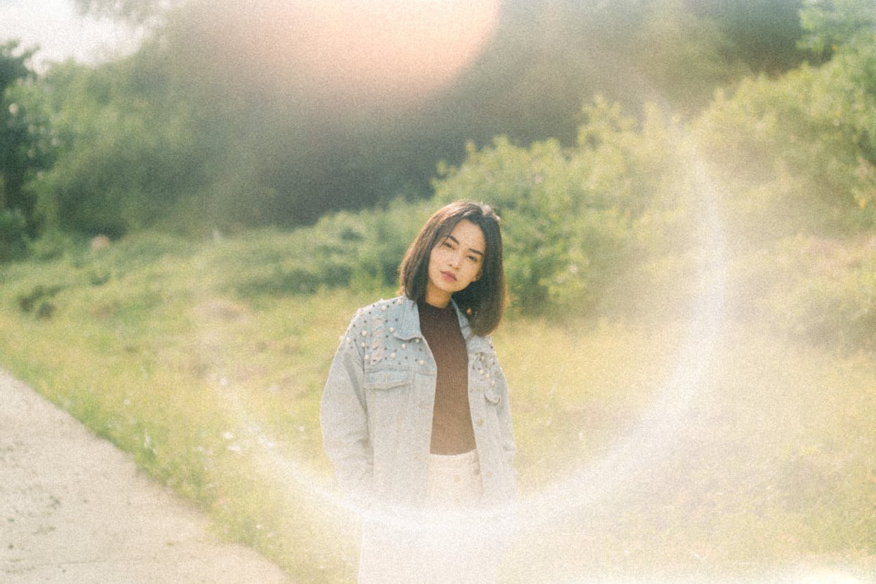 A woman standing in front of a road with a sun shining