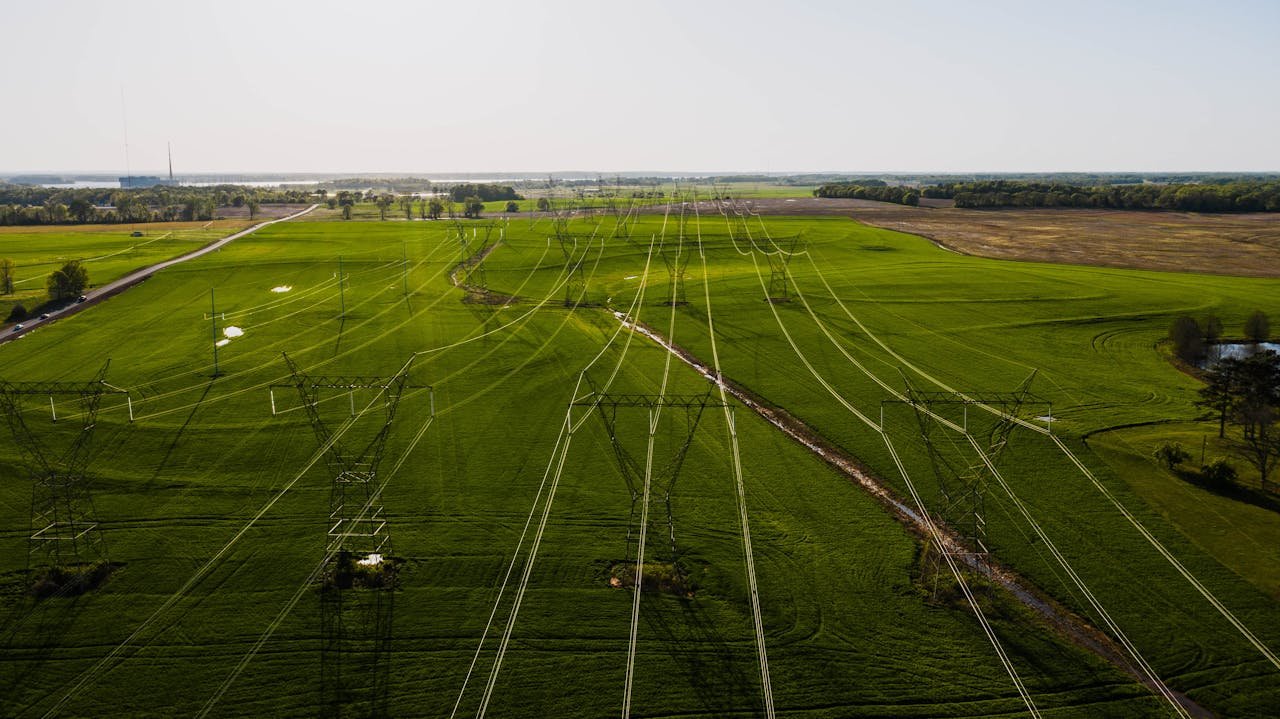 Drone view of meadow with fresh verdant grass and electric power station in daytime in summer